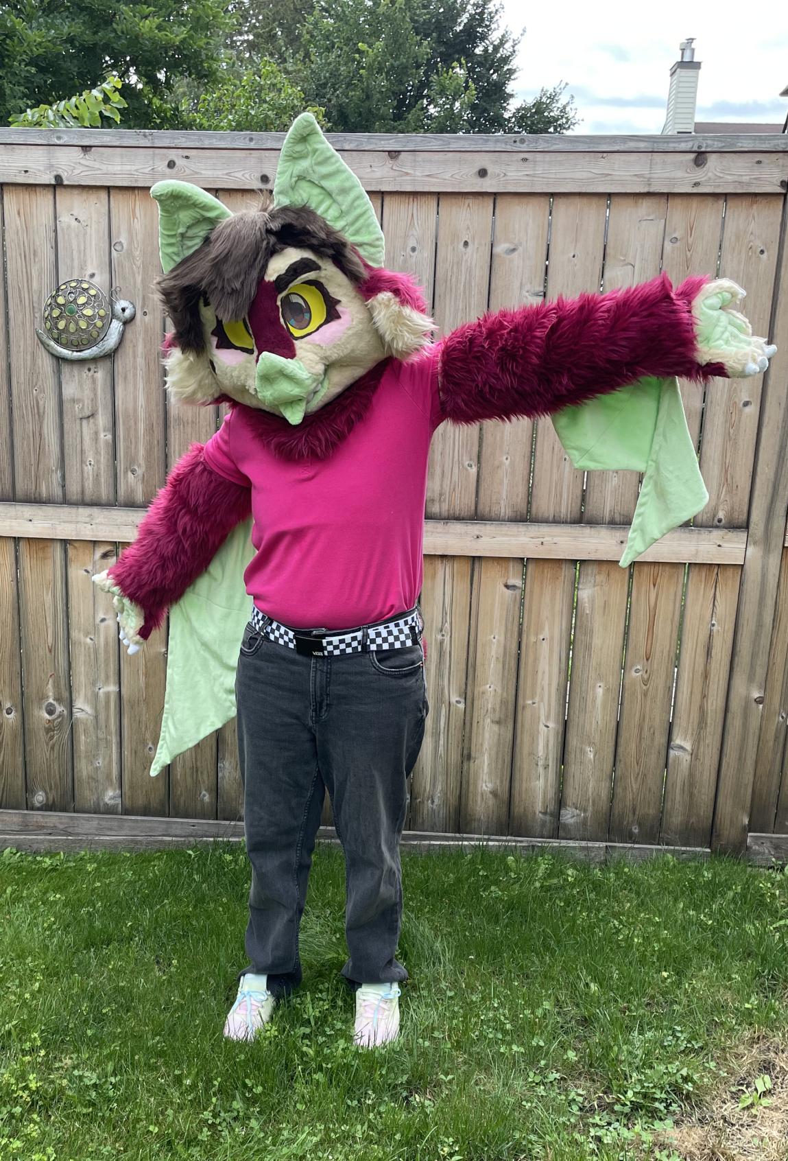 The bat fursuiter with his arms stretched outwards to show off his wings.